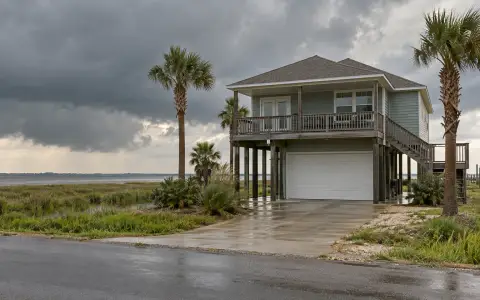 A raised coastal house with a steel garage door on the ground level