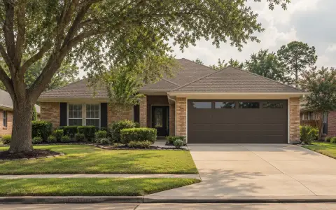 A brick ranch house with a new dark bronze insulated garage door